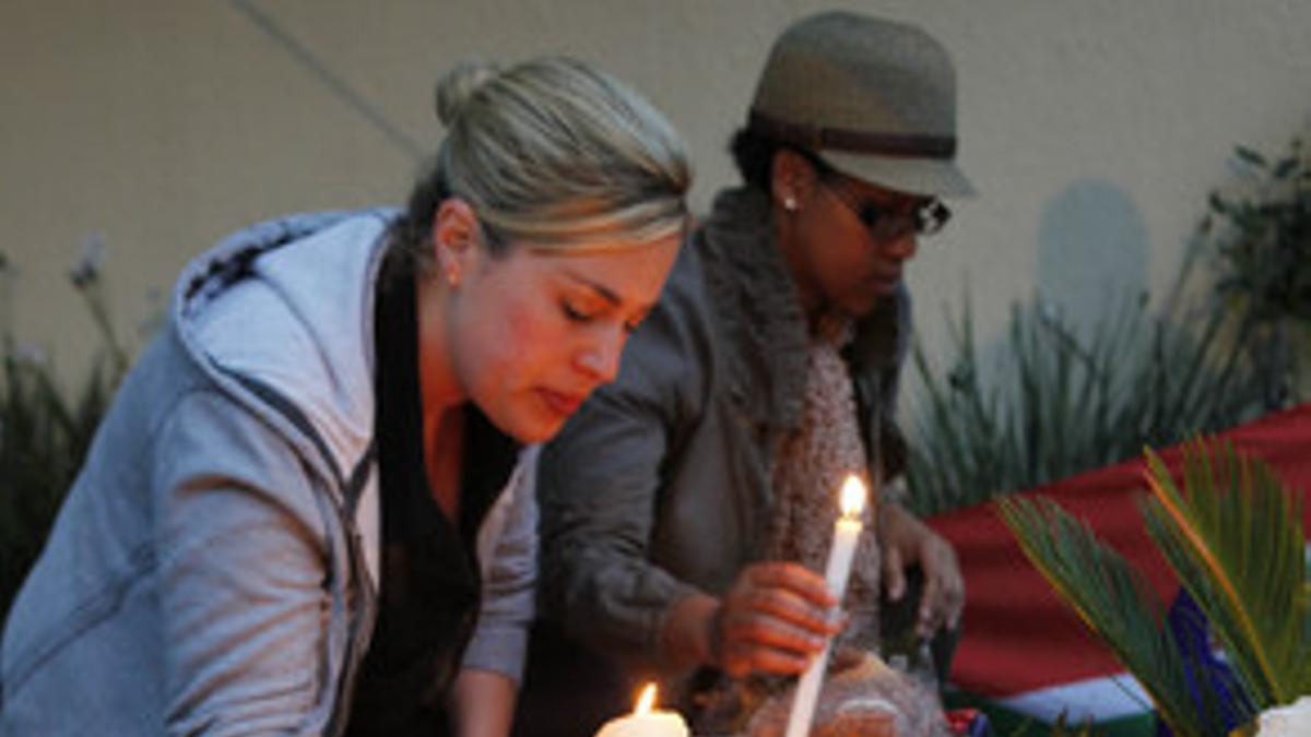 Una mujer encience una vela ante la casa de Mandela, en Johannesburgo, este viernes.