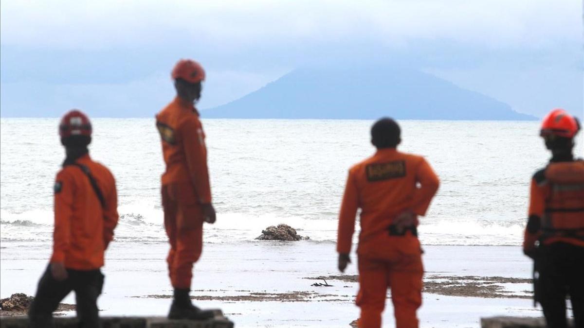 Miembros de los servicios de rescate observan la actividad del volcán Anak Krakatau desde la playa indonesia de Carita.