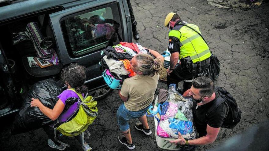 Vecinos de Todoque evacuan ayer a toda prisa viviendas del barrio con la ayuda de un miembro de la Unidad Militar de Emergencias. | | ANDRÉS GUTIÉRREZ