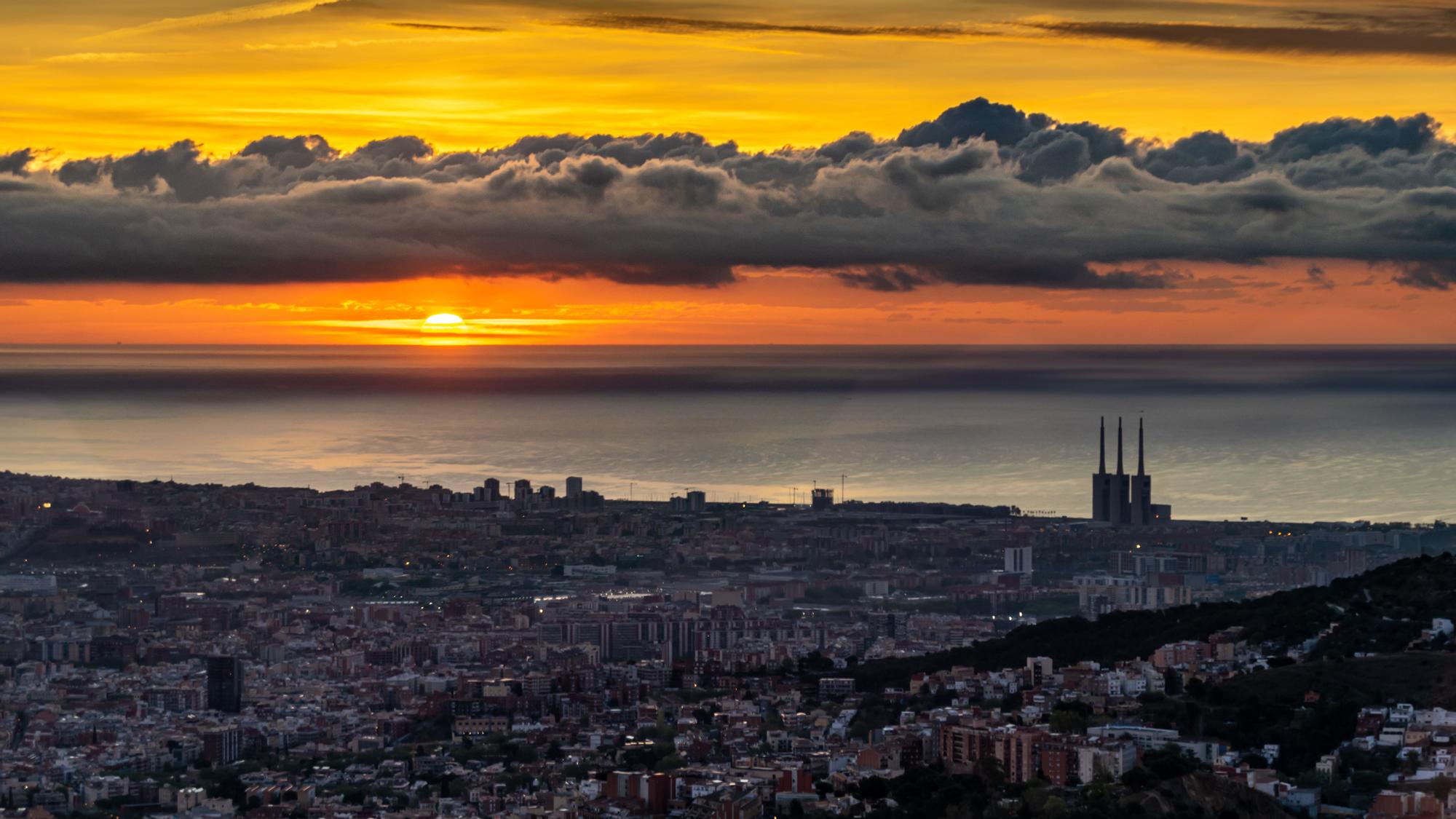 Amanecer en Barcelona sol y franja de nubes bajas