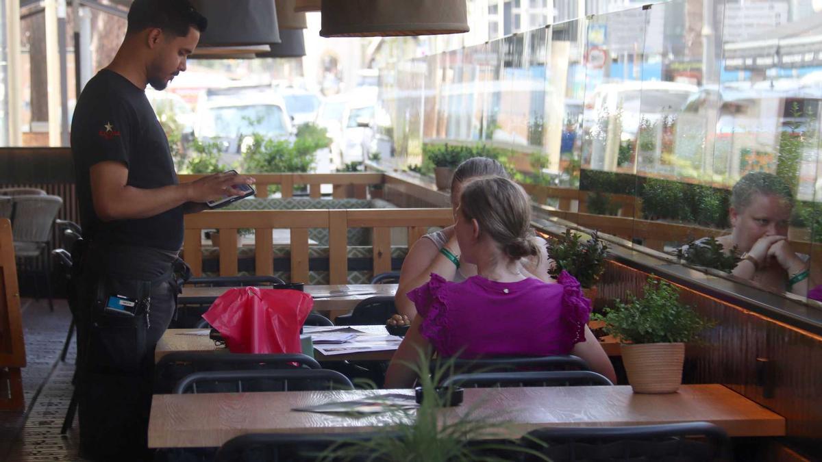 Un cambrer pren nota a dues turistes en una terrassa de Platja d'Aro.