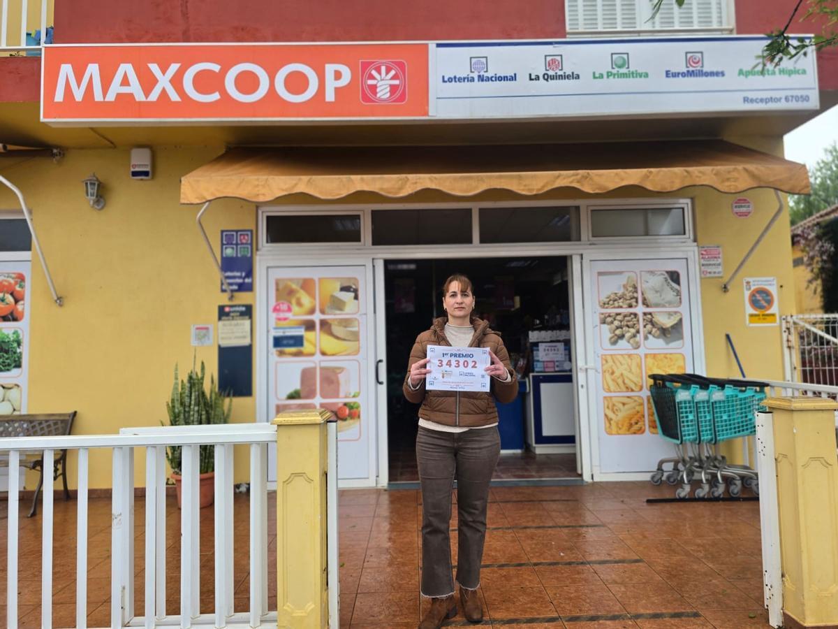 Silvia Candelario Castro, dueña del supermercado Super La Palma (Puntagorda), este sábado, con el cartel del primer premio del Sorteo Especial de la Lotería Nacional por el Día del Padre