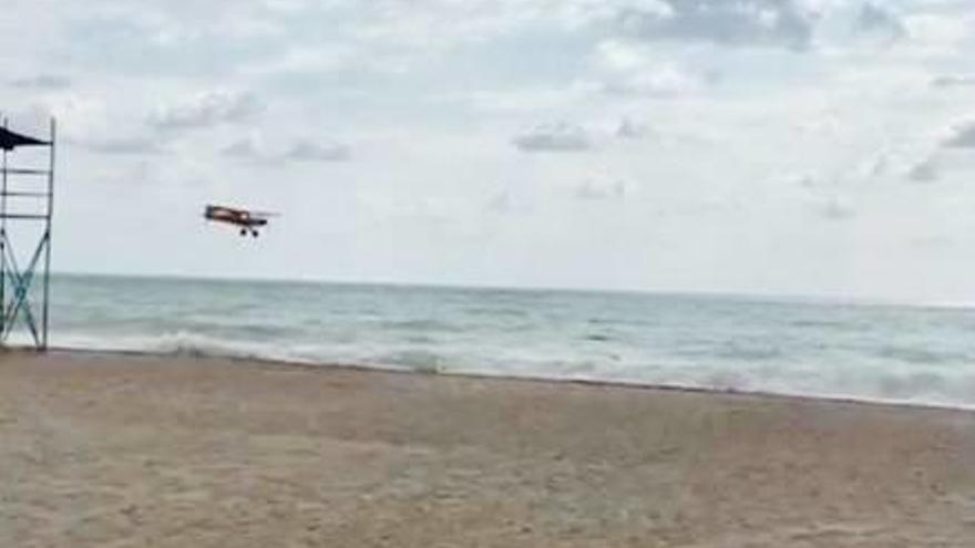 La avioneta sobrevolando a baja altura la playa del Port.