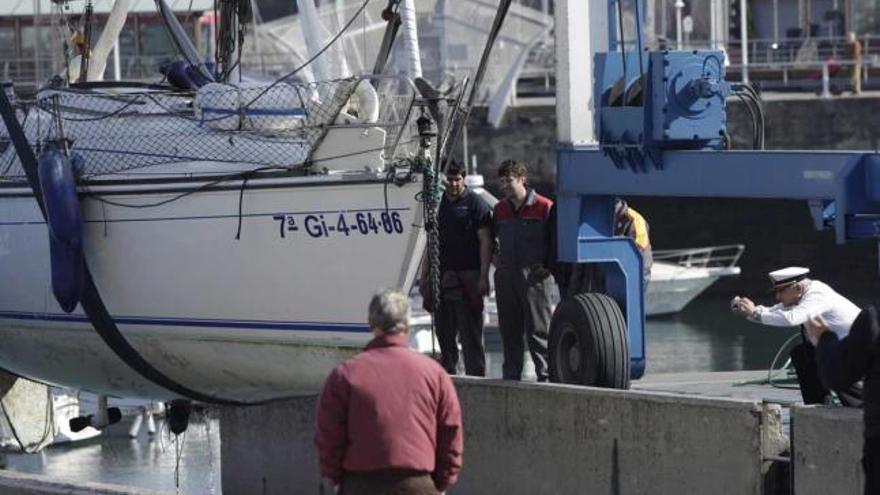 El barco encallado en el puerto deportivo, izado para su traslado.