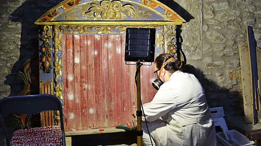 Una de las restauradoras trabajando en una parte del retablo. | Adrián Herrero