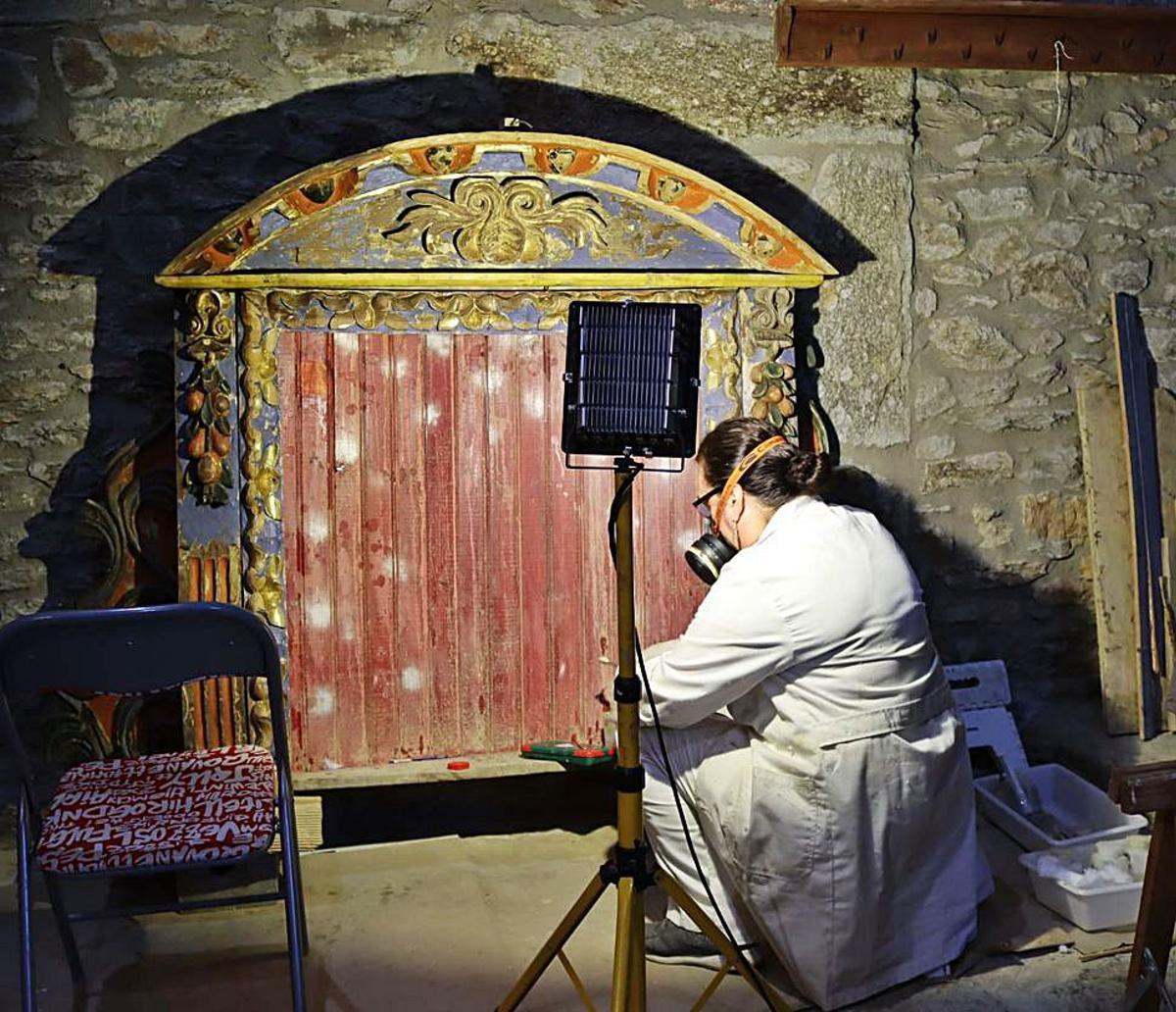 Una de las restauradoras trabajando en una parte del retablo. | Cedida