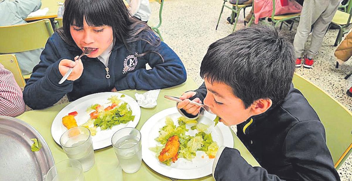 Dos alumnos comiendo lechuga recogida en su Aula da Natureza.