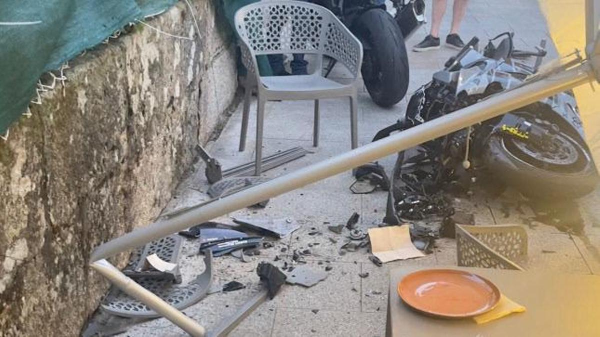 La moto del accidente en el suelo y los daños en la terraza del restaurante Volver, en Bueu.