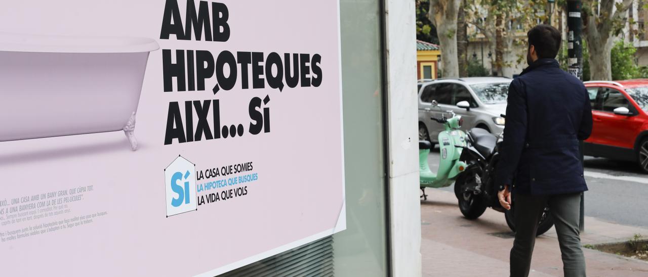 Un ciudadano pasa frente al escaparate de una entidad   financiera en el que se publicita un préstamos hipotecario.