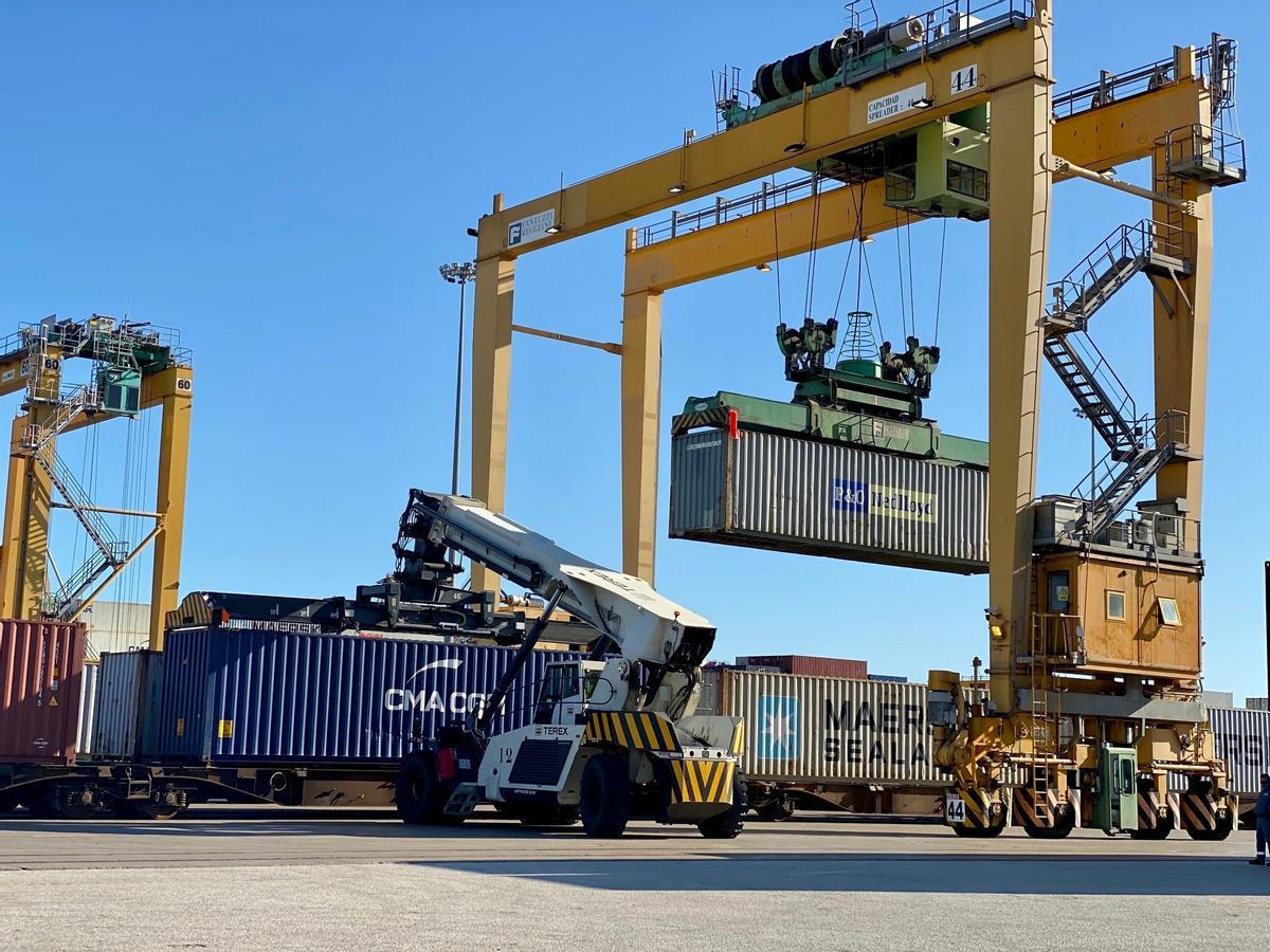 Una grúa carga un contenedor en un tren en el Puerto de València.