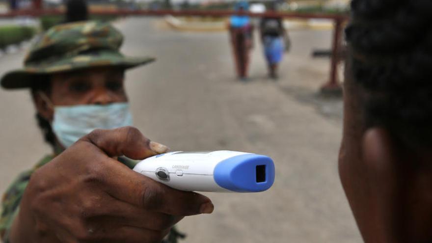 Un militar toma la temperatura a un joven.