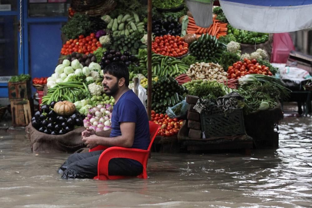 Un vendedor de frutas y verduras espera clientes sentado en mitad de una inundación, después de las lluvias en Lahore, Pakistán. REUTERS/Mohsin Raza