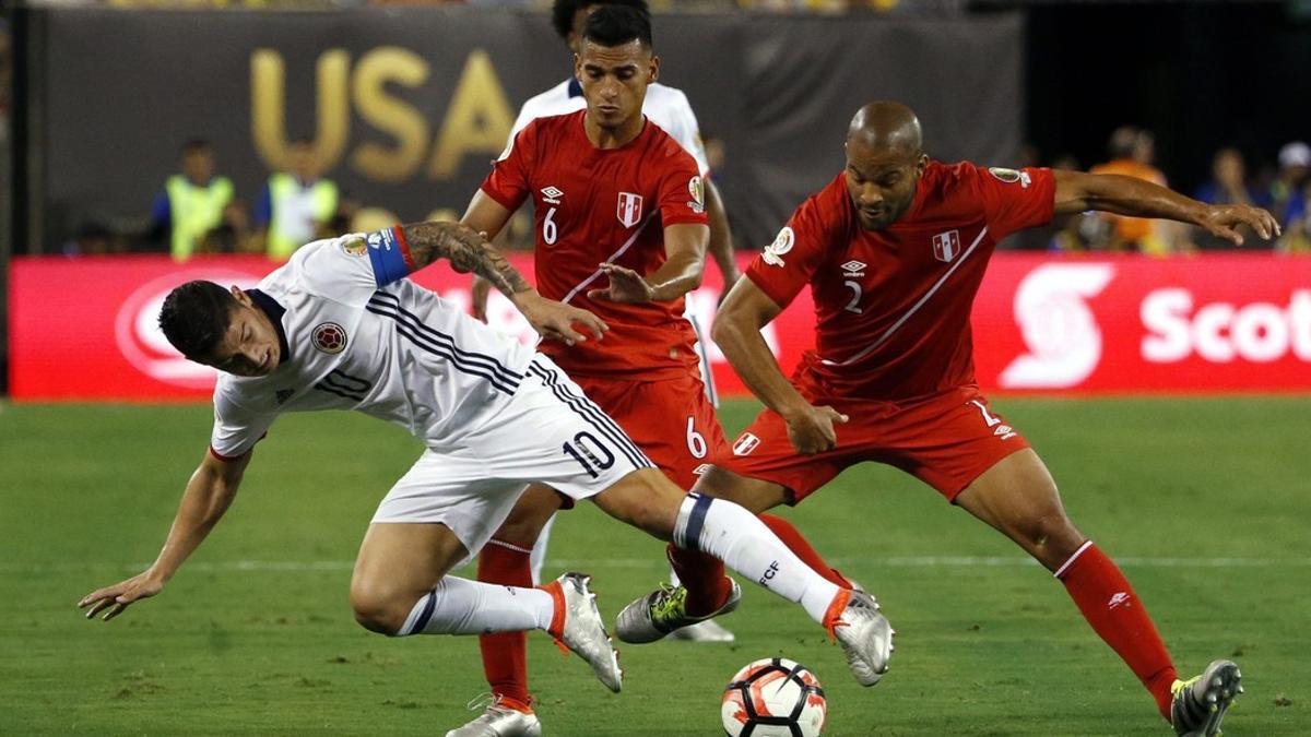 El colombiano James Rodriguez pugna por el balón con los peruanos Alberto Rodriguez y Miguel Trauco