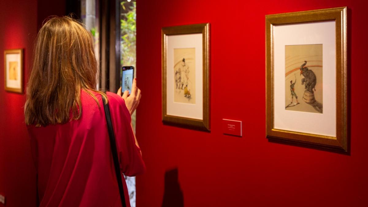 Una visitante fotografía algunos cuadros de esta muestra.