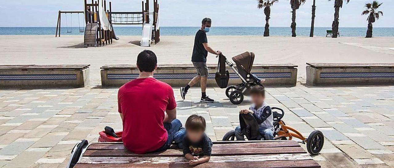 Varios padres con sus hijos, por el paseo de la playa de San Juan.