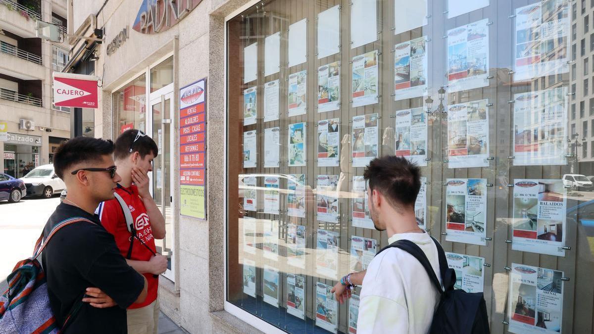 Jóvenes viendo en una inmobiliaria anuncios de viviendas, casas y pisos en alquiler, especialmente escasos para universitarios.
