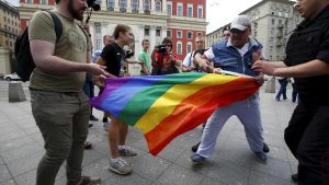 Un hombre intenta retirar la bandera LGTBI a un grupo de manifestantes en favor de los derechos de la comunidad, en el centro de Moscú en mayo de 2015.