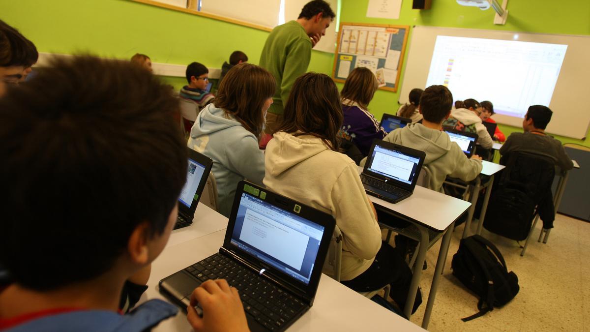Imagen de archivo de un grupo de alumnos con portátiles en un aula catalana.