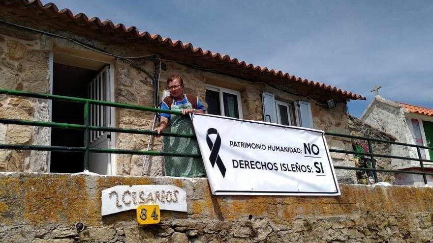 Victoria, que vive en Ons todo el año junto a su marido Cesáreo, en su casa con una pancarta.