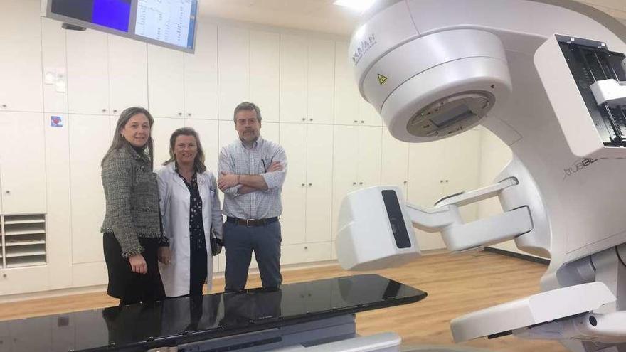 María José López-Rebollo, directora de Recursos Económicos; Eloína Núñez Masid, gerente; y Antonio Gómez Caamaño, jefe de servizo de oncología radioterápica de la XXIS, junto a uno de los aceleradores.