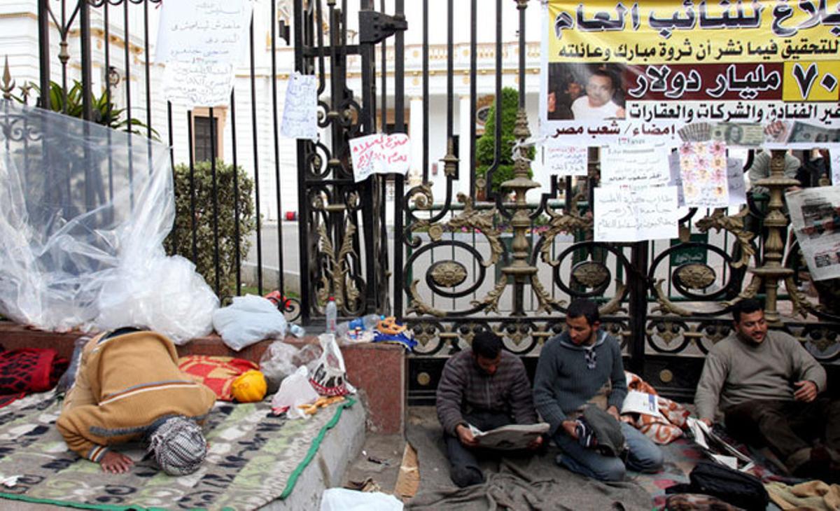 Un egipci resa amb altres persones acampades al costat d’una de les portes del Parlament.