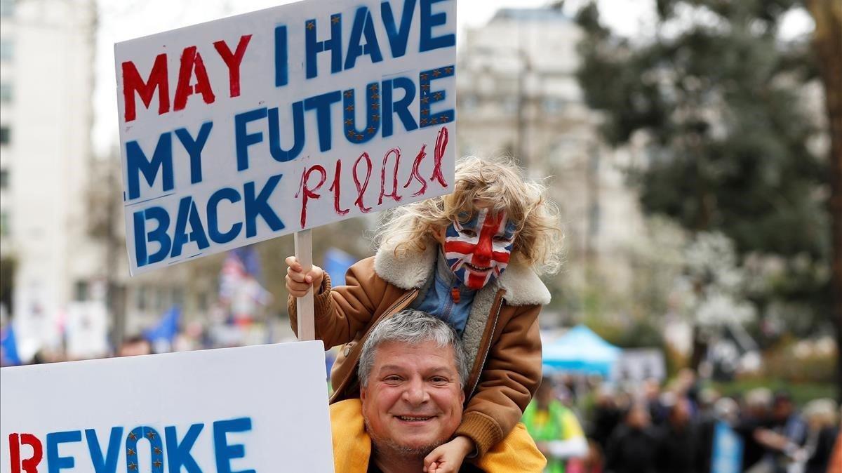 Un partidario de la UE lleva a un niño sobre sus hombros pidiendo al gobierno que dé a los británicos una votación sobre el acuerdo final del Brexit mientras participan en la marcha de la votación popular en el centro de Londres.