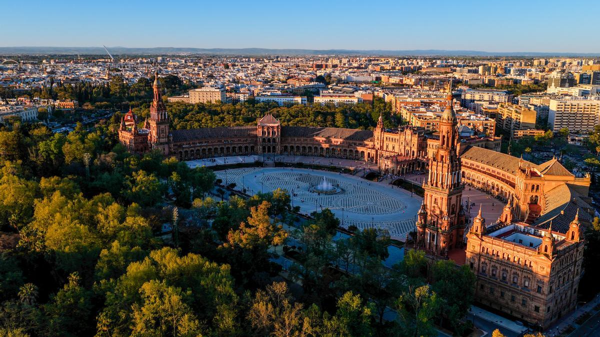 Vista aérea de la Plaza de España en Sevilla con arquitectura semicircular y torres gemelas, un monumento histórico rodeado por el Parque María Luisa en Andalucía