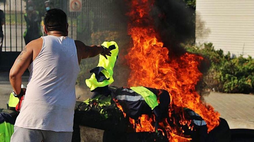 Un empleat d&#039;Acciona llança una armilla a una foguera ahir a la Zona Franca.