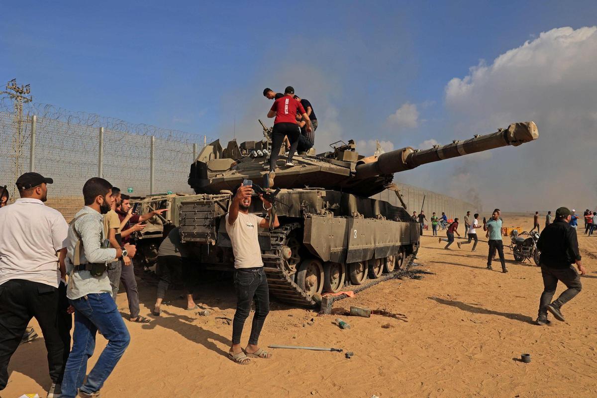 Ciudadanos palestinos se apoderan de un tanque israelí tras cruzar la valla fronteriza con Israel desde Khan Yunis en la parte suroeste de la Franja de Gaza.