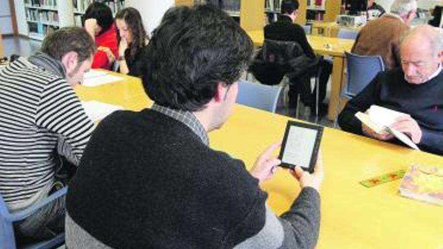 Un hombre lee con un dipositivo electrónico en la sala de lectura de la Biblioteca.