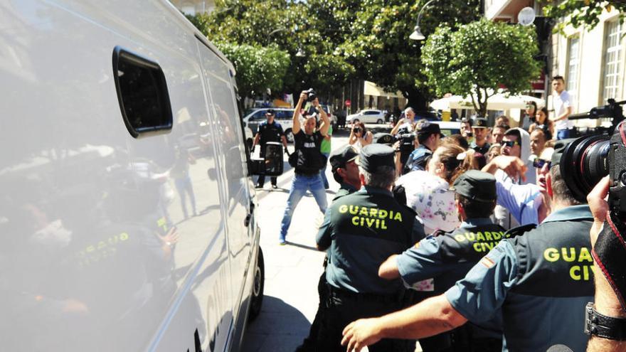 Un grupo de vecinos, contenidos por los agentes al paso del furgón que trasladaba al parricida. // I. A.