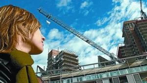 Una joven observa unas obras de construcción de pisos en Barcelona.