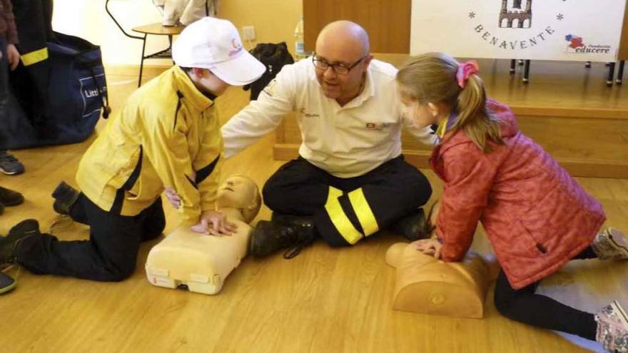 Un niño y una niña practican la reanimación cardiopulmonar con maniquís.