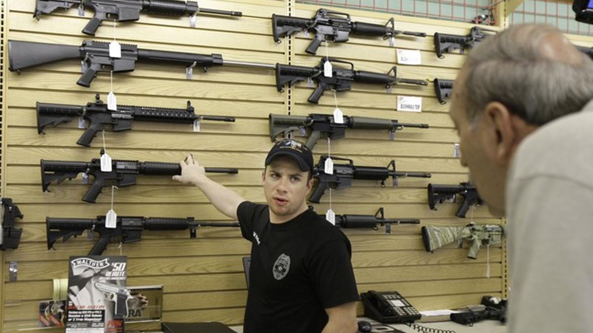 El dependiente de una tienda de armas de Fort Worth (Tejas) explica las características de un rifle a un cliente.