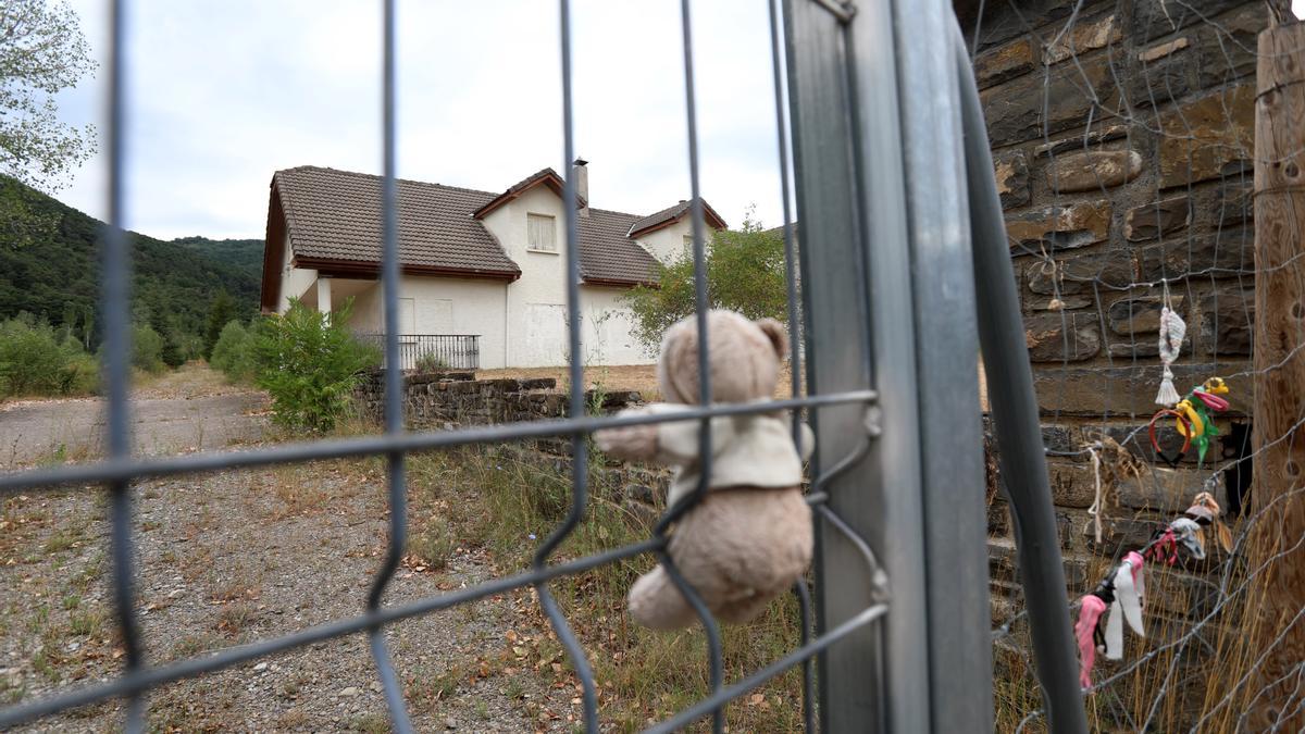 Un osito de peluche y, al fondo, el antiguo edificio de servicios, lo único que quedó en pie.