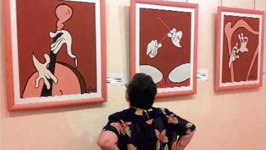 Una dona observa les pintures de Xavier Cugat.