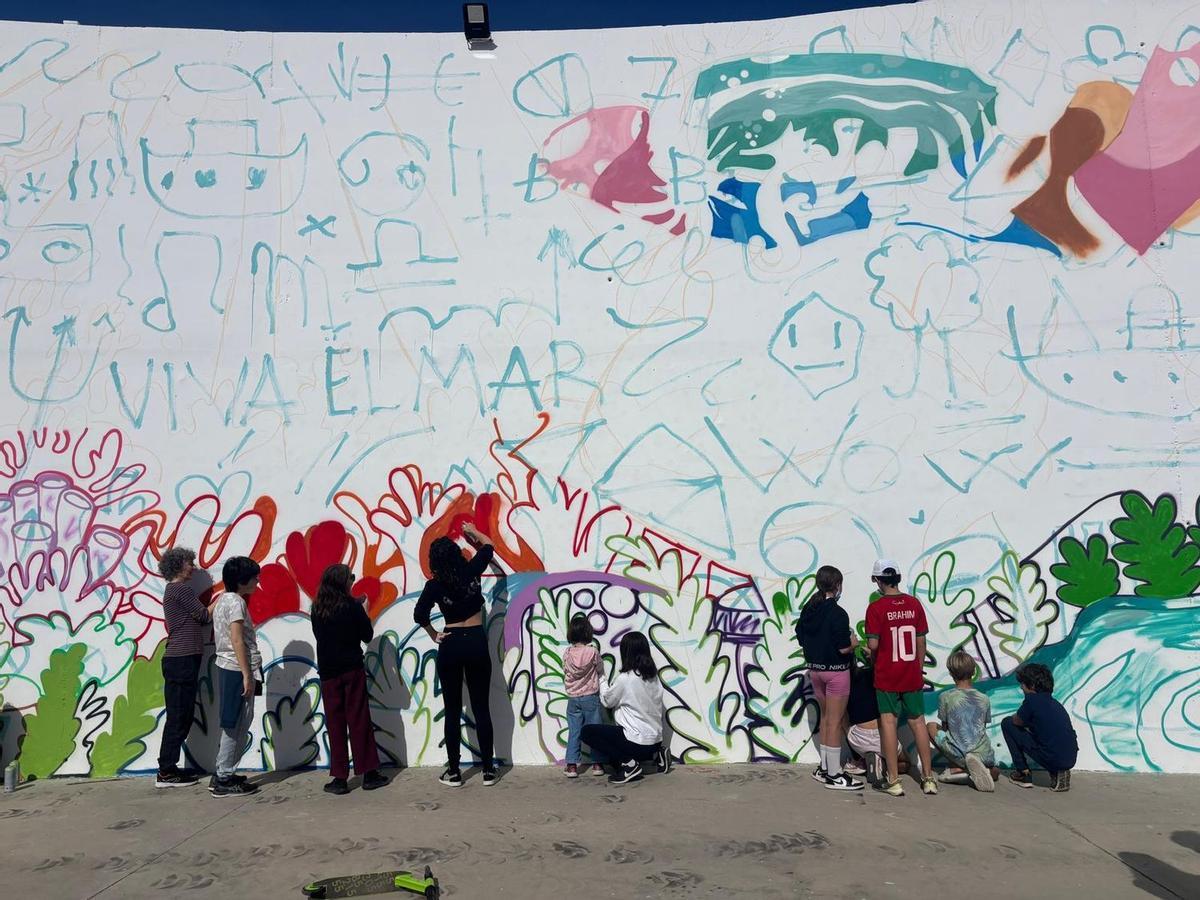 Niños, niñas y jóvenes pintan uno de los murales urbanos de este festival en una pared de Almassora.