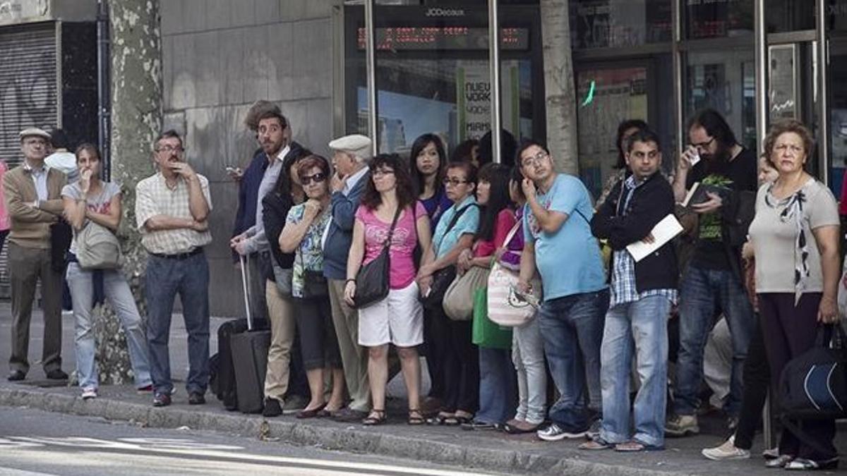 Usuarios del autobús esperan en una parada de la calle de Aribau, el lunes.