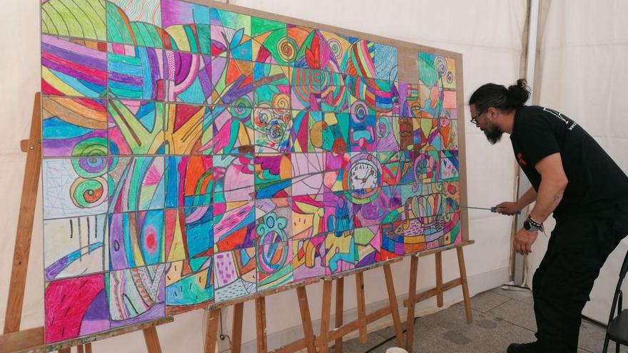 Carlos Adeva remata el mural inspirado en Antonio Machado creado en un taller de la Feria del Libro. | M. J. C.