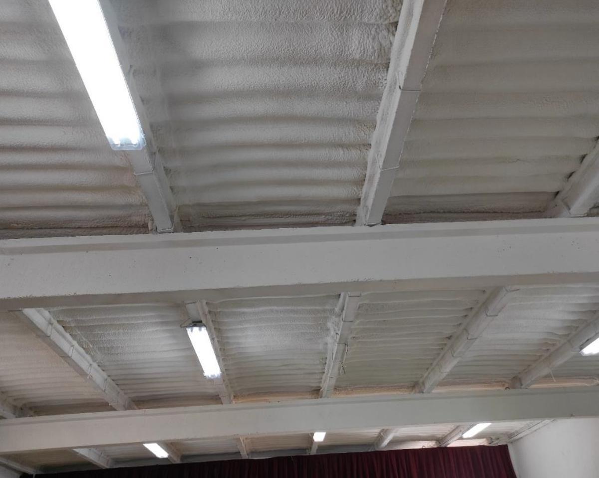 Interior del edificio polivalente, con vigas en T sobre las que descansan viguetas prefabricadas, sobre las que existe una cobertura de fibrocemento con espuma de poliuretano proyectada.