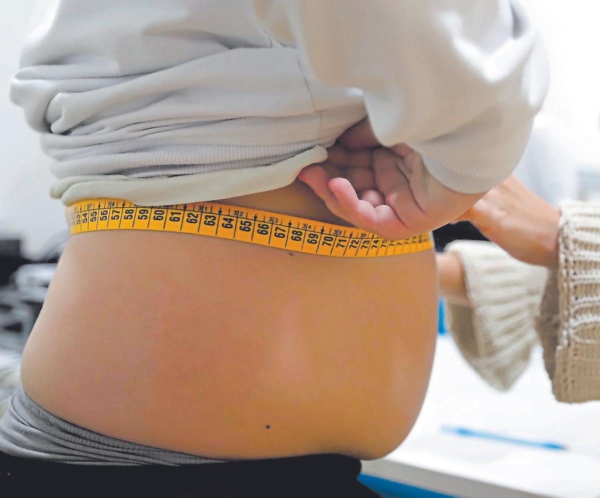 Una especialista mide el contorno de la cintura de una paciente.