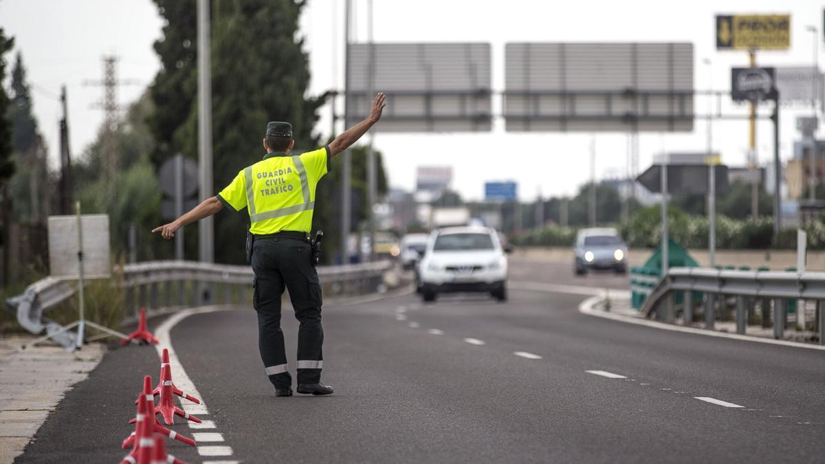 Un agente de la Guardia Civil de Tráfico da el alto a un conductor en un control,