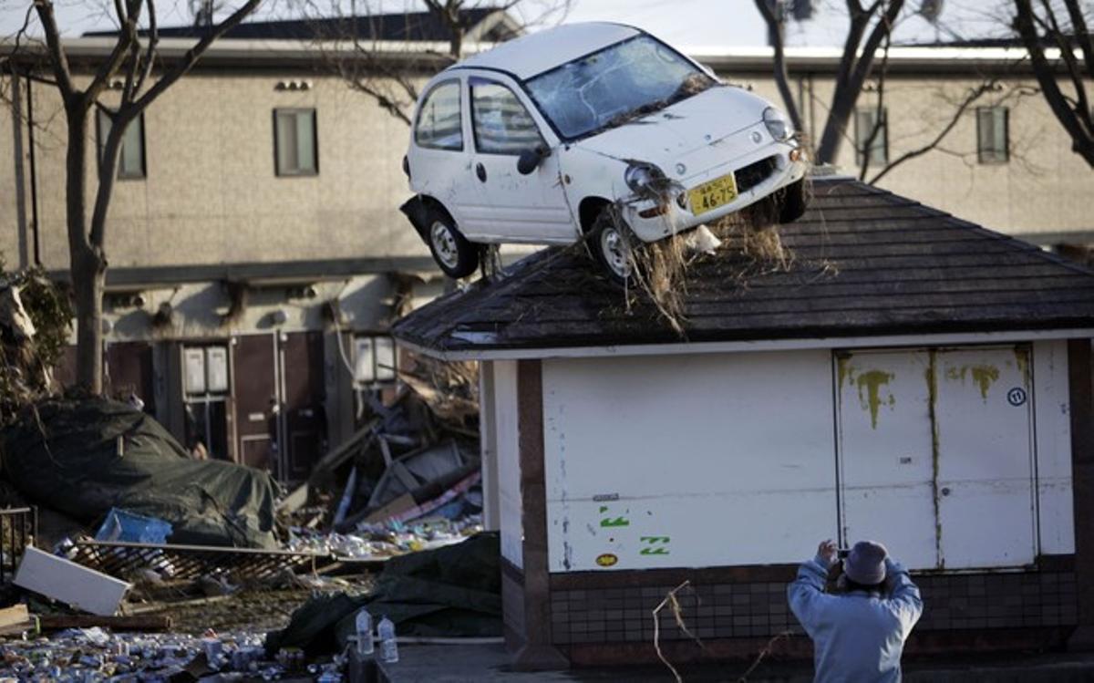 Un home fa fotos del desastre causat per un tsunami a Sendai. Un home fa fotos del desastre causat per un tsunami a Sendai.