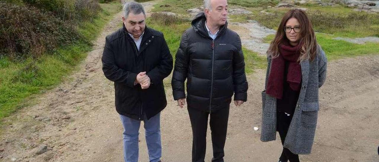 Luis Aragunde, Gonzalo Durán y Nuria Morgade con el paso de agua que corta la senda a sus espaldas. // Noé Parga