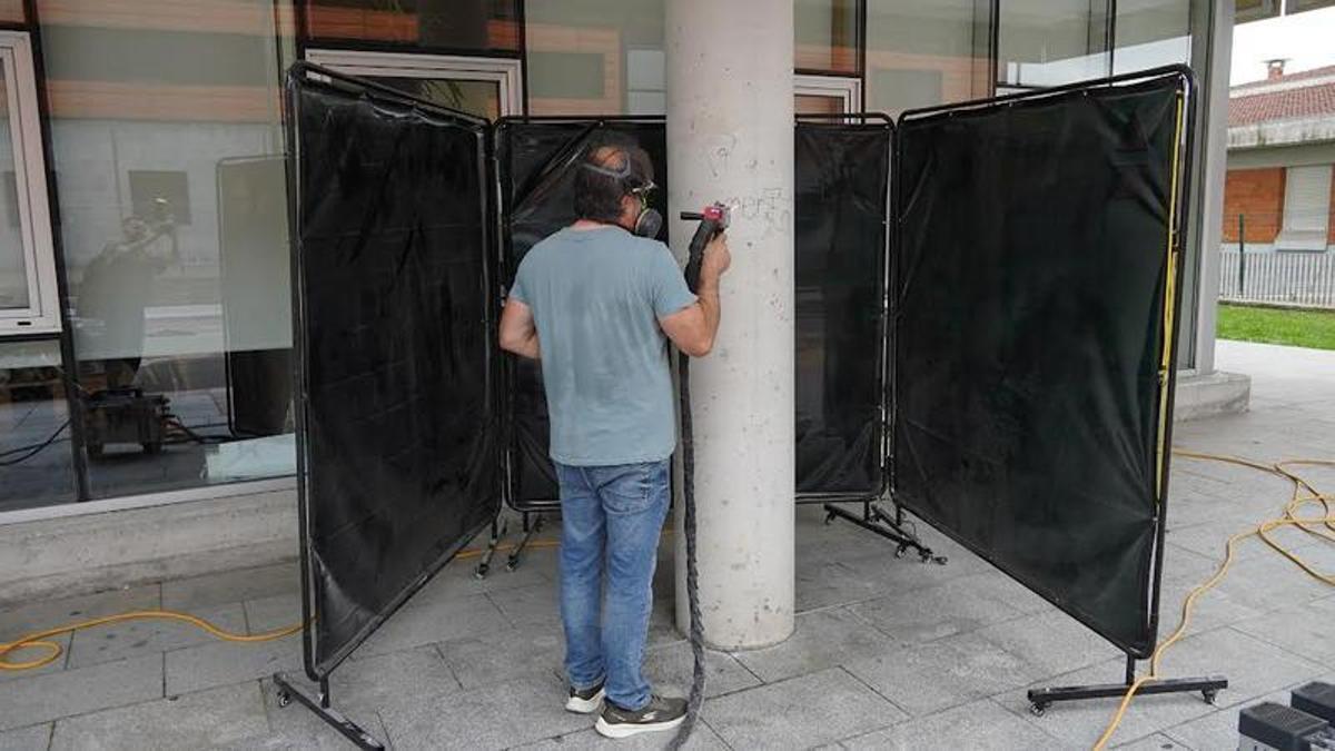 Un operario limpia una pintada en el centro polivalente integrado de Lugones.