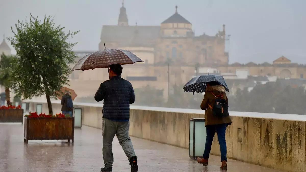 Viandantes con paraguas en el Puente Romano de Córdoba en un día de lluvia.