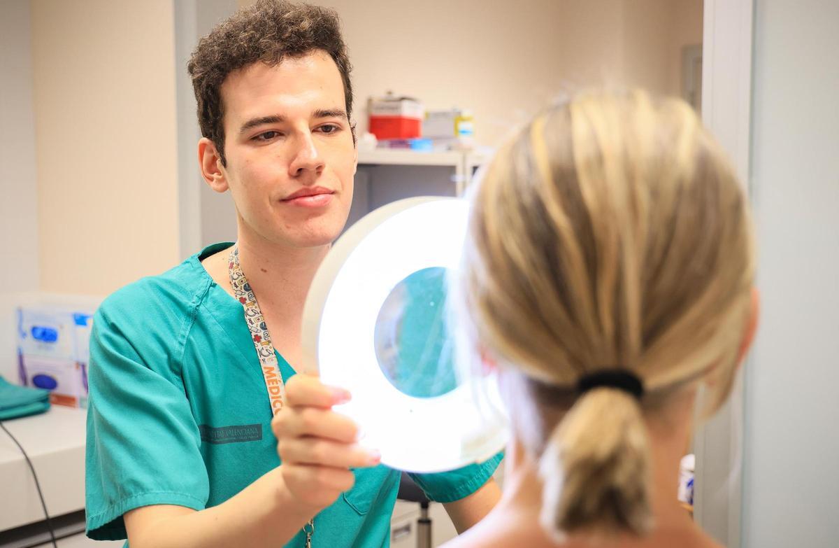 El residente en Dermatología de La Fe, Miguel Lasheras, analiza la piel de una paciente.