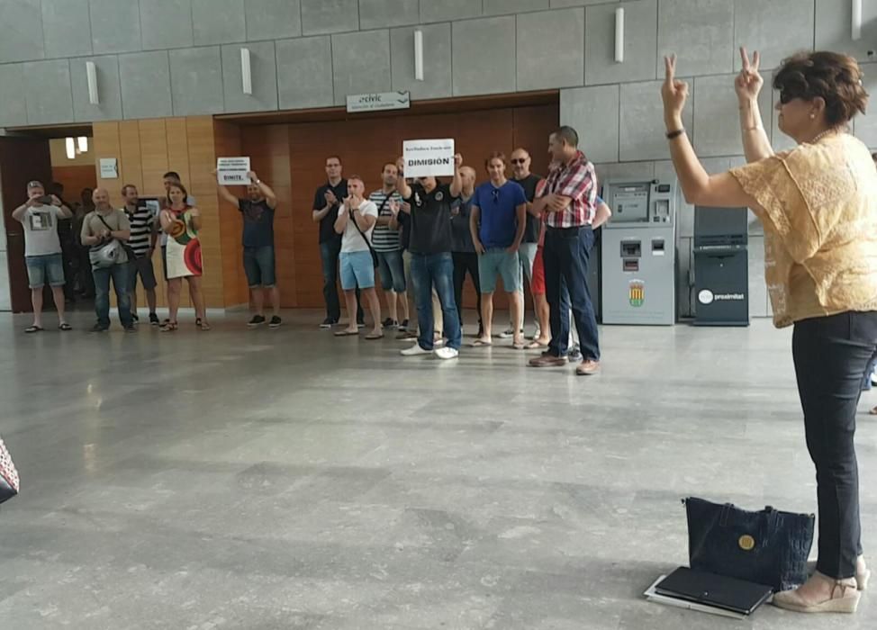 Policía local y trabajadores de la brigada de mantenimiento esperan a la concejala con carteles pidiendo su renuncia, a lo que la edil de Sí se puede responde con aplausos y con el símbolo de la victo