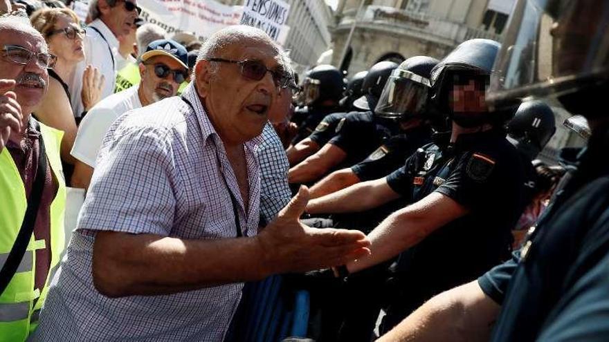 Un grupo de pensionistas protesta ante la Policía a las puertas del Congreso de los Diputados. // Efe