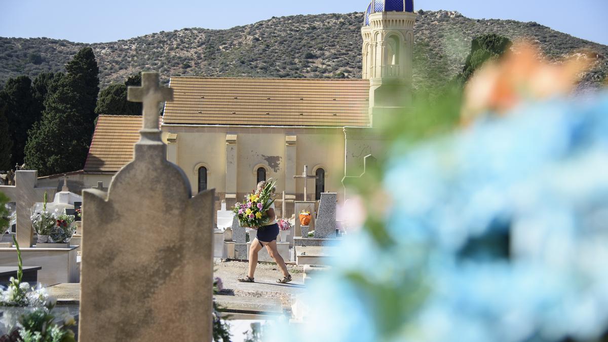 Una persona camina con un centro de flores en la mano, este día 1 en el cementerio de Cartagena.